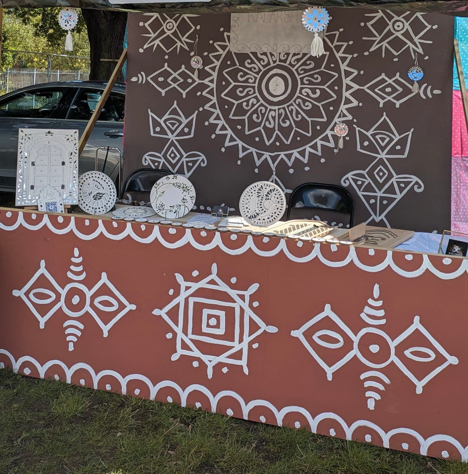 Kalarshi's stall painted with white Lippan-style motifs on terracotta and brown, with mirror pieces on display