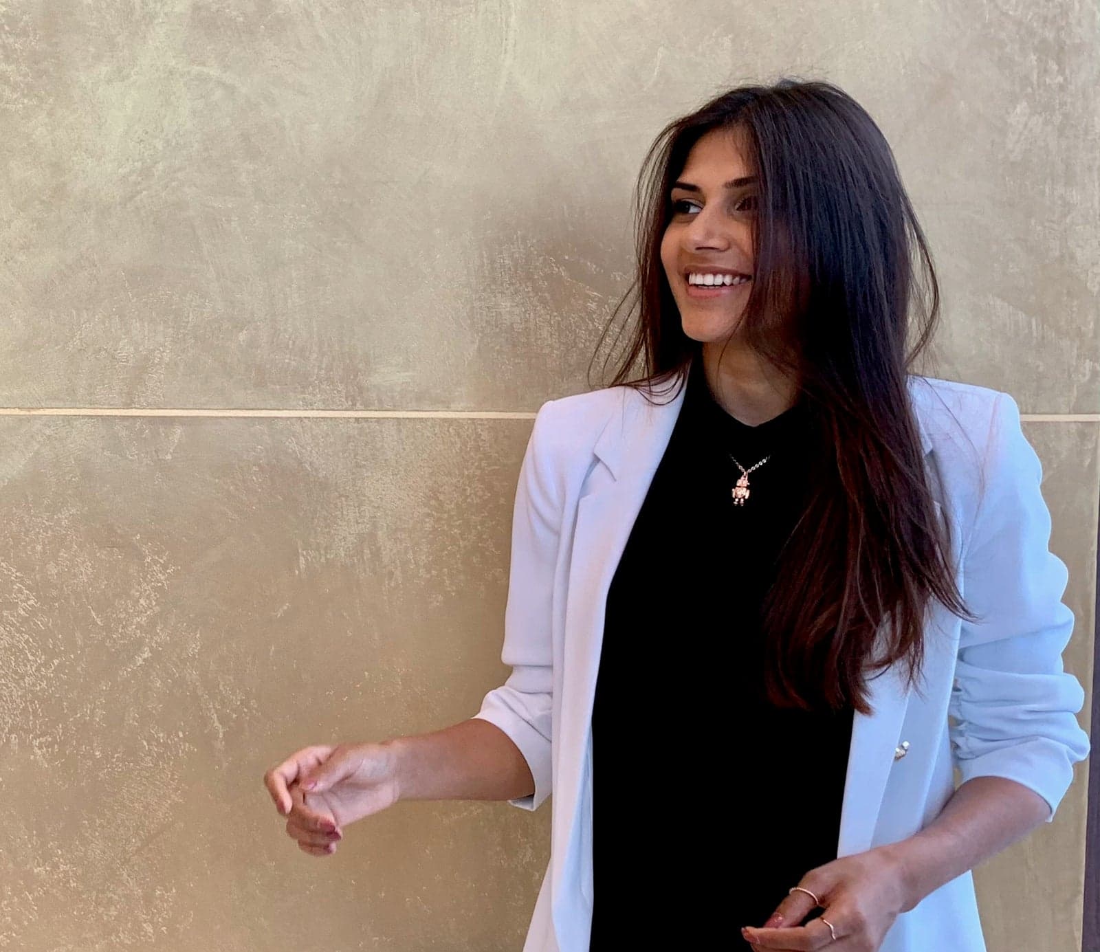 Astha Desai-Hill laughing against a gold textured wall